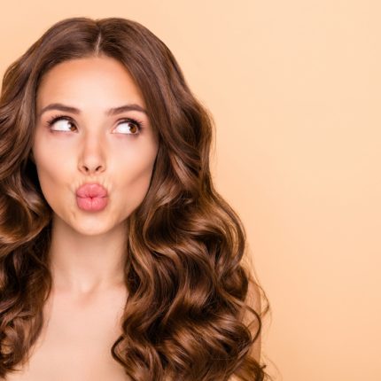 Close-up portrait of her she nice-looking attractive sweet gorgeous girlish curious wavy-haired girl looking aside sending kiss pout lips copy space isolated over beige pastel color background | Bellava Aesthetics in Crestview Hills, KY